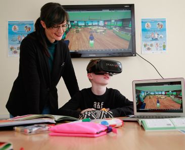Child using a VR headset at a desk with a researcher beside them