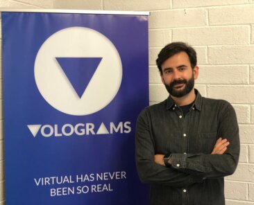 Volograms team member beside a Volograms banner